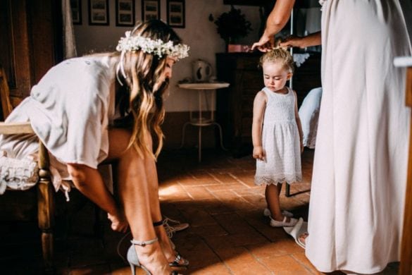 Bride puts on her shoes witnessed by little child