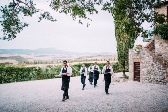 Waiters serve food at borgo with courtyard with panoramic view of Val d'Orcia