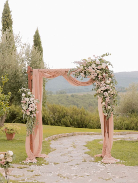 Stylish wedding arch in blush tones with flowers and drapes by Con Amore wedding planners in Tuscany.