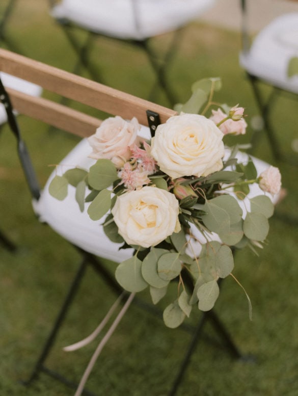 Blush and white floral wedding chair decoration with roses and eucalyptus.