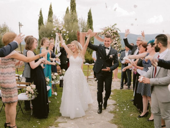 Happy wedding couple exits ceremony setting at garden wedding in Tuscany.