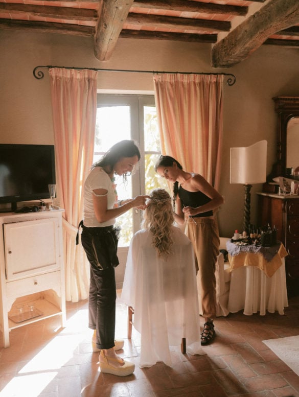 Bride is getting ready with hair dresser and make up artist.