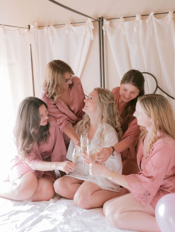 Bride and her bridesmaids drink prosecco in blush colored kimono robes.