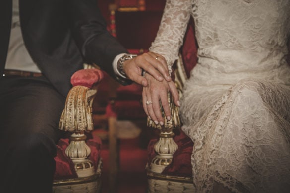 Groom touches his wife's hand after wedding ring exchange